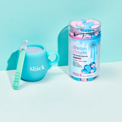 Canister of Dream Clouds Hard Wax Beads for Face & Body with pink and blue cloud beads on a stylized blue background next to a blue microwave cup. 