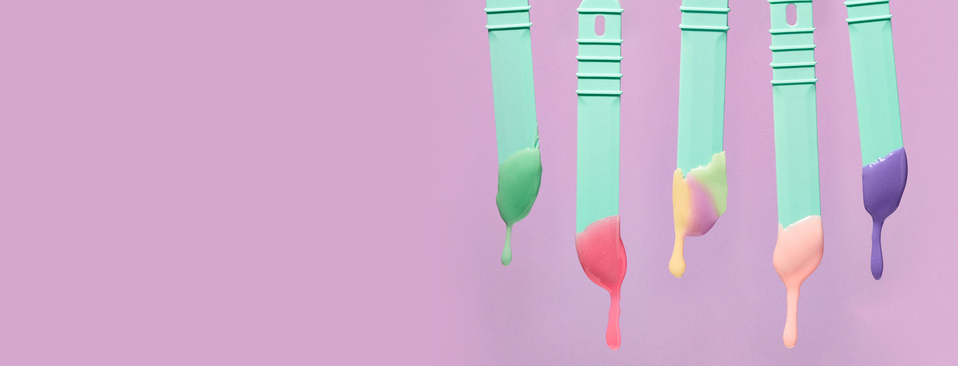 Teal colored sticks with melted wax on them, on a pink background