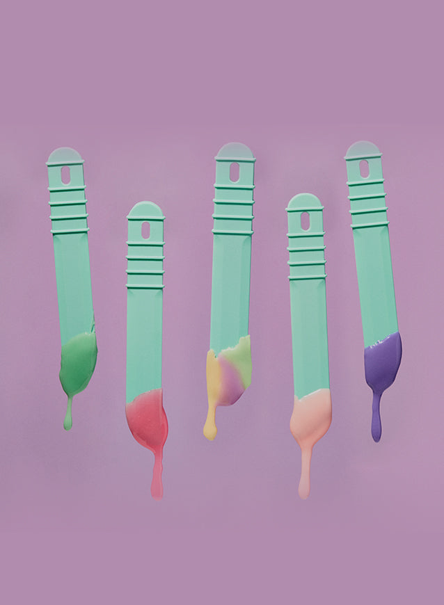 Teal colored sticks with melted wax on them, on a pink background